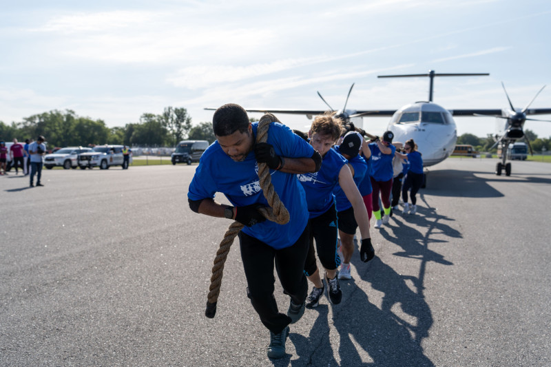 A group of individuals pulling a plane with a rope