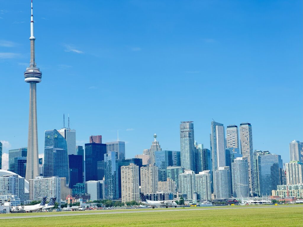 Plane landing at Billy Bishop Toronto City Airport with Toronto skyline.